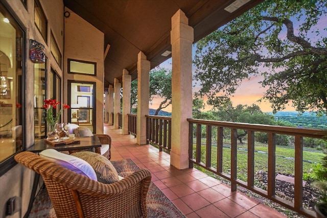 balcony at dusk featuring covered porch