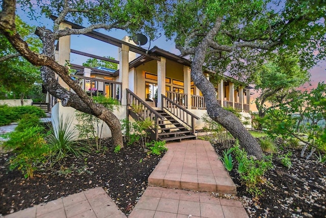 view of front of property with a porch, stairs, and stucco siding