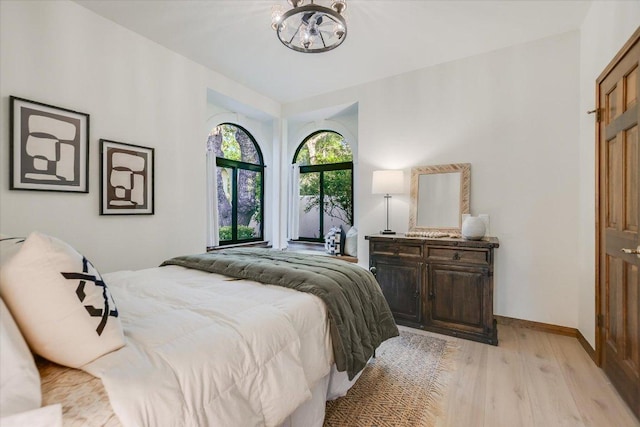 bedroom with baseboards, a chandelier, and light wood-style floors