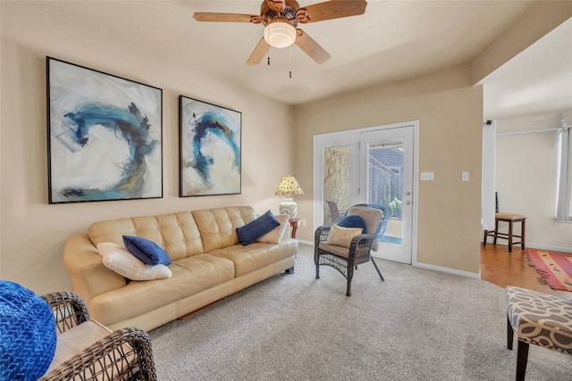 carpeted living area with baseboards and ceiling fan