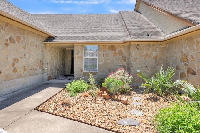 entrance to property with roof with shingles and stone siding