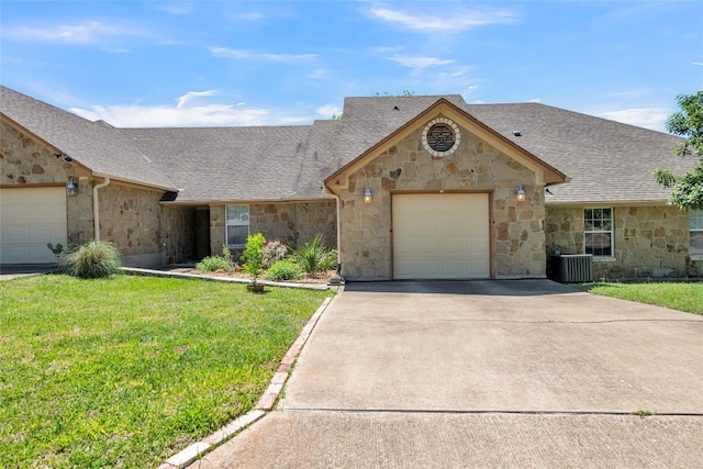 view of front of property featuring a front yard, roof with shingles, concrete driveway, an attached garage, and stone siding