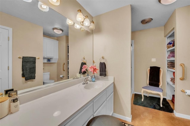 bathroom featuring baseboards, vanity, and toilet