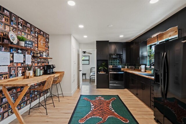 326 W Mulberry St, Fredericksburg, TX 78624 - kitchen featuring dark cabinets, recessed lighting, light wood-style floors, and black appliances