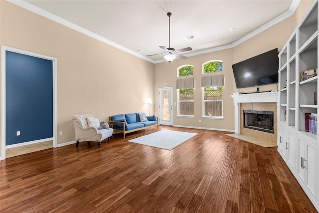 814 Arrowhead Trl, Cedar Park, TX 78613 - living room featuring a tile fireplace, a ceiling fan, wood finished floors, crown molding, and built in features