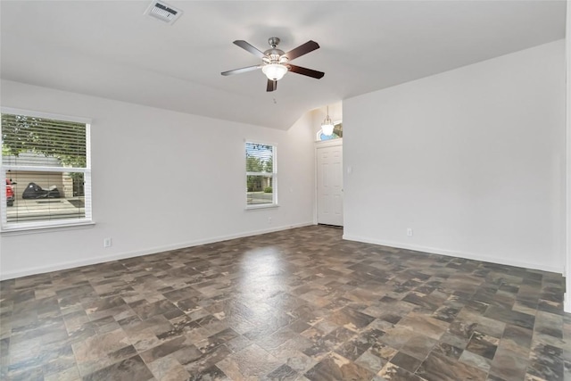 spare room featuring stone finish floor, visible vents, baseboards, and ceiling fan