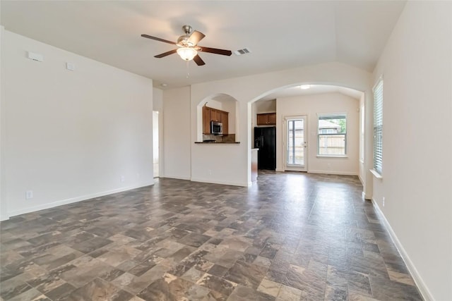 unfurnished living room featuring visible vents, a ceiling fan, arched walkways, stone finish flooring, and baseboards