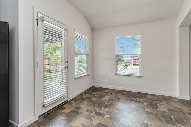 interior space with baseboards, vaulted ceiling, and stone finish floor