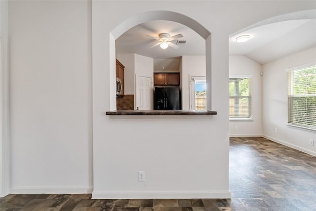 421 Capistrano Dr, San Marcos, TX 78666 - unfurnished living room with arched walkways, ceiling fan, vaulted ceiling, and dark stone finish flooring
