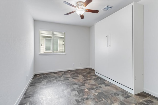 unfurnished room featuring visible vents, baseboards, stone finish floor, and ceiling fan