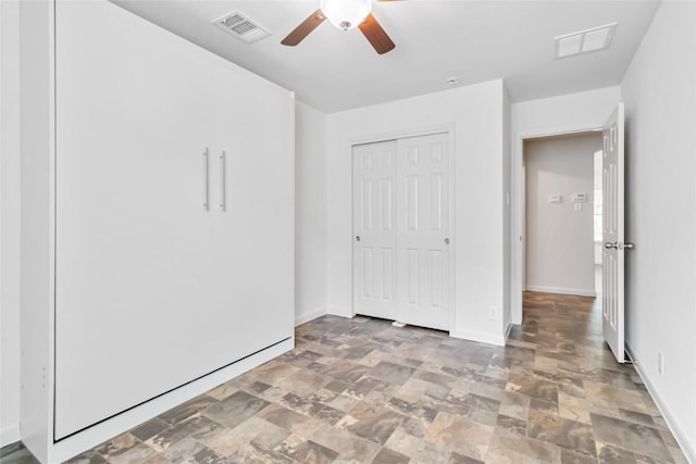 unfurnished bedroom featuring baseboards, visible vents, stone finish flooring, and a closet