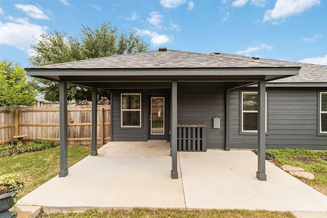 back of house with fence, a patio area, and a shingled roof
