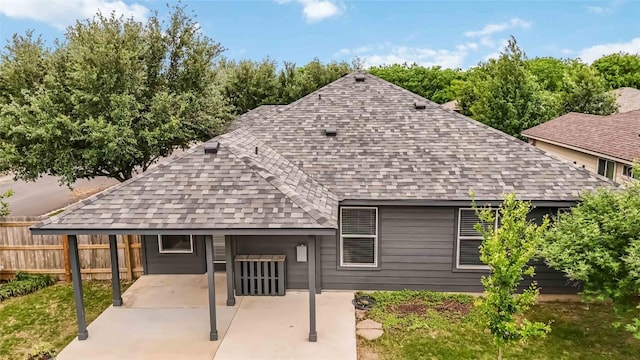 back of property with a shingled roof and fence