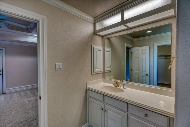 bathroom with a textured wall, vanity, and ornamental molding