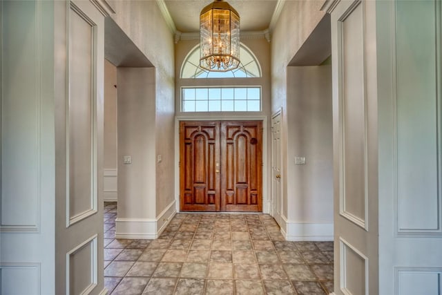 entrance foyer with baseboards, ornamental molding, and a chandelier