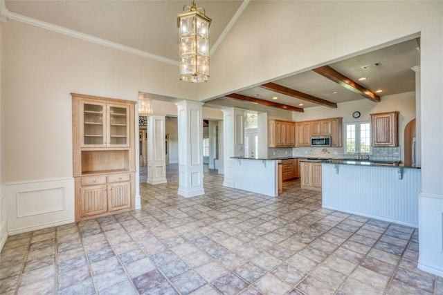 kitchen with stainless steel microwave, a peninsula, dark countertops, and ornate columns
