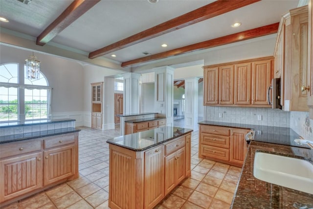 kitchen with a center island, a wealth of natural light, beam ceiling, and a sink