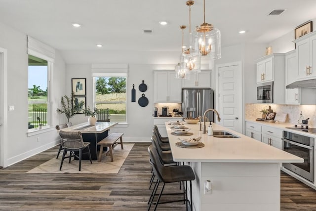 237 San Xavier St, Georgetown, TX 78633 - kitchen with stainless steel appliances, a sink, dark wood-style flooring, light countertops, and a center island with sink