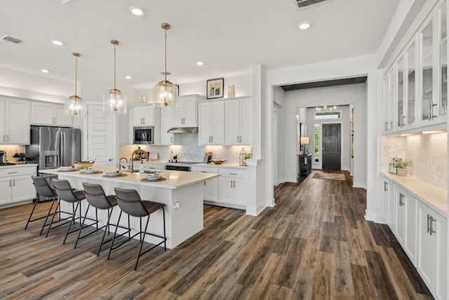 237 San Xavier St, Georgetown, TX 78633 - kitchen featuring stainless steel appliances, decorative backsplash, white cabinetry, a breakfast bar area, and dark wood-style flooring