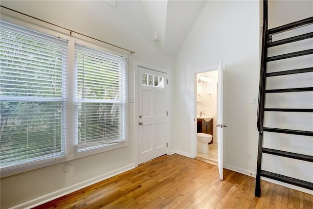 entrance foyer with lofted ceiling, light wood-style floors, and baseboards
