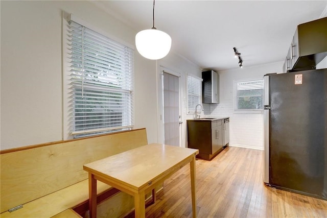 kitchen with light countertops, track lighting, a sink, freestanding refrigerator, and light wood-style flooring