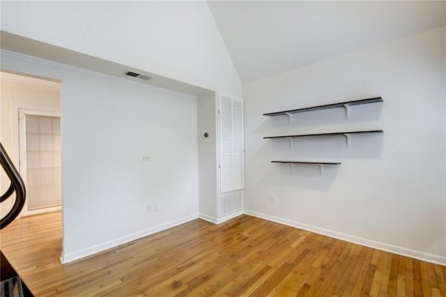 unfurnished living room with vaulted ceiling, wood finished floors, visible vents, and baseboards