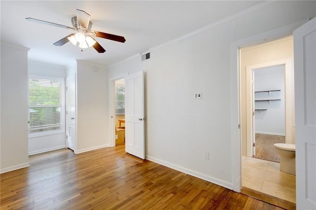 unfurnished room with wood finished floors, visible vents, a ceiling fan, and crown molding
