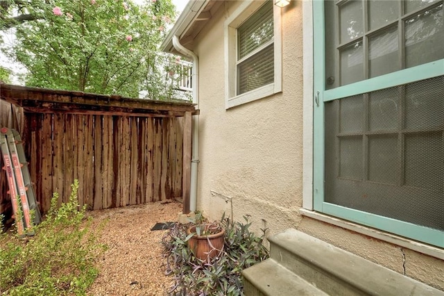 view of property exterior featuring fence, entry steps, and stucco siding