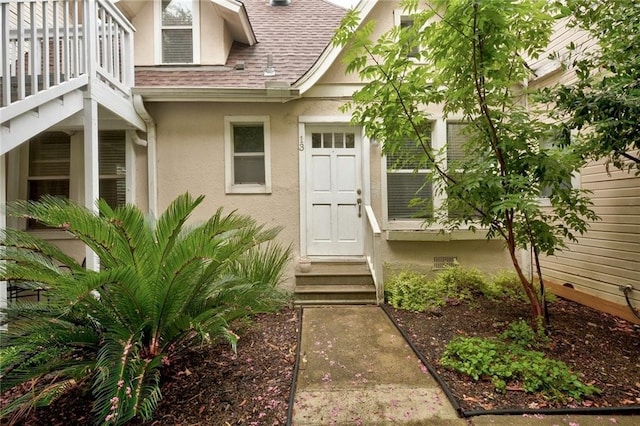 doorway to property with a shingled roof and stucco siding