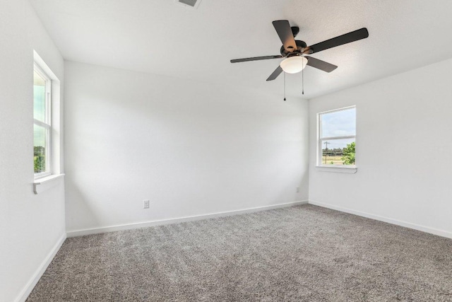 carpeted empty room with baseboards, a ceiling fan, and visible vents