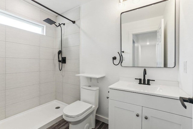 bathroom featuring tiled shower, wood finished floors, vanity, and toilet