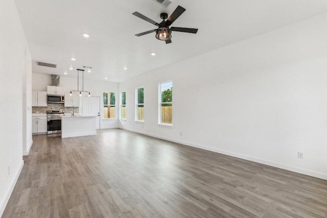 unfurnished living room featuring baseboards, wood finished floors, visible vents, and recessed lighting