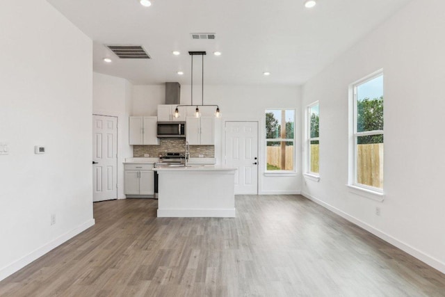 kitchen with light wood-type flooring, stainless steel appliances, light countertops, baseboards, and visible vents