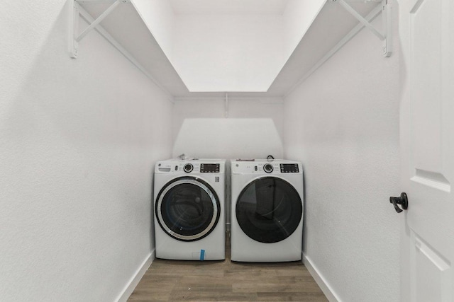 laundry area with washing machine and dryer, wood finished floors, baseboards, and laundry area