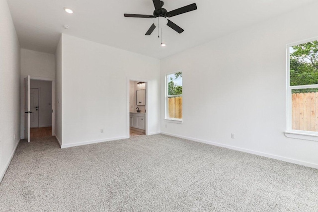unfurnished bedroom featuring light colored carpet, baseboards, a ceiling fan, and connected bathroom