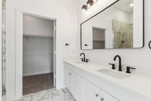full bath with a spacious closet, marble finish floor, a sink, and a marble finish shower