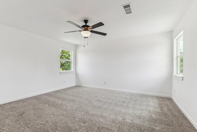 empty room with baseboards, visible vents, carpet floors, and ceiling fan