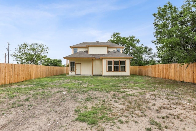 rear view of property featuring a shingled roof and a fenced backyard