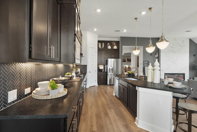 2104 Tobiano Trce, Georgetown, TX 78633 - kitchen with dark countertops, stainless steel appliances, a kitchen bar, dark brown cabinets, and decorative backsplash