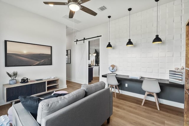 2104 Tobiano Trce, Georgetown, TX 78633 - living room with a barn door, ceiling fan, wood finished floors, and baseboards