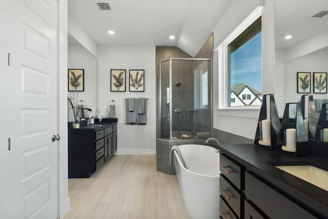 2104 Tobiano Trce, Georgetown, TX 78633 - full bathroom featuring a shower stall, two vanities, recessed lighting, a freestanding tub, and vaulted ceiling