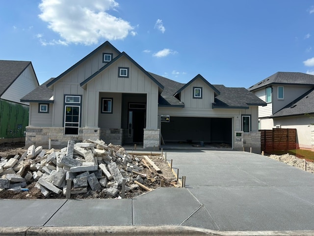 2104 Tobiano Trce, Georgetown, TX 78633 - view of front facade featuring board and batten siding, driveway, roof with shingles, and stone siding