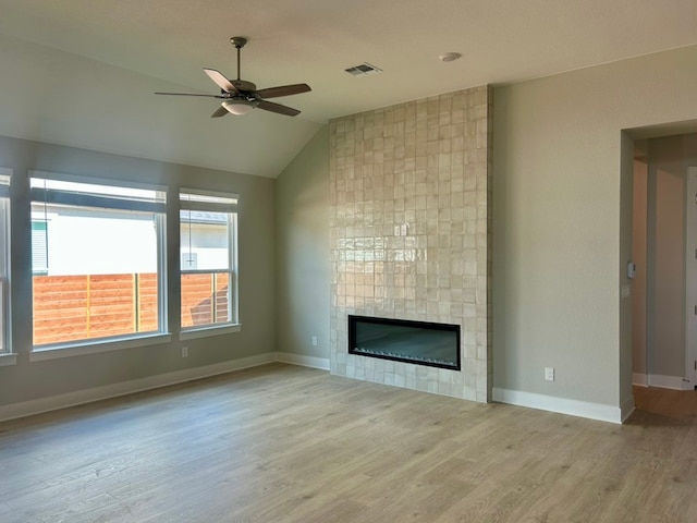 2104 Tobiano Trce, Georgetown, TX 78633 - unfurnished living room with a ceiling fan, wood finished floors, a tiled fireplace, and vaulted ceiling