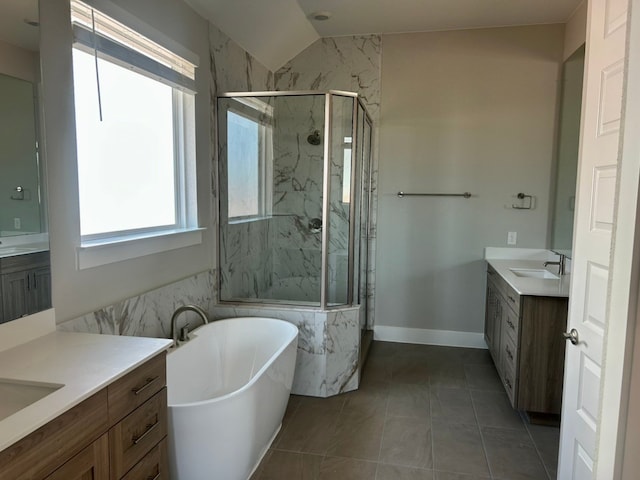 2104 Tobiano Trce, Georgetown, TX 78633 - bathroom with two vanities, a marble finish shower, a freestanding bath, tile patterned flooring, and vaulted ceiling