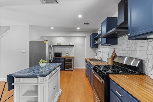 3400 Santa Fe Dr, Austin, TX 78741 - kitchen with open shelves, stainless steel appliances, blue cabinets, wine cooler, and wall chimney range hood