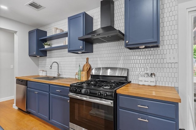 3400 Santa Fe Dr, Austin, TX 78741 - kitchen featuring appliances with stainless steel finishes, wall chimney exhaust hood, wood counters, and blue cabinets
