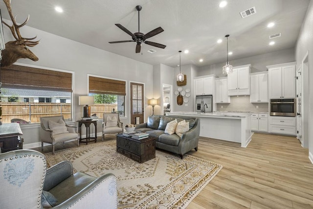 living room with recessed lighting, visible vents, light wood finished floors, and ceiling fan