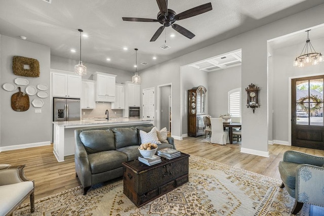living area featuring recessed lighting, light wood-style floors, visible vents, and ceiling fan with notable chandelier