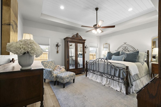 bedroom with recessed lighting, a raised ceiling, light wood-style flooring, and access to exterior