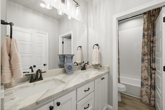 bathroom featuring toilet, wood finished floors, a sink, and double vanity